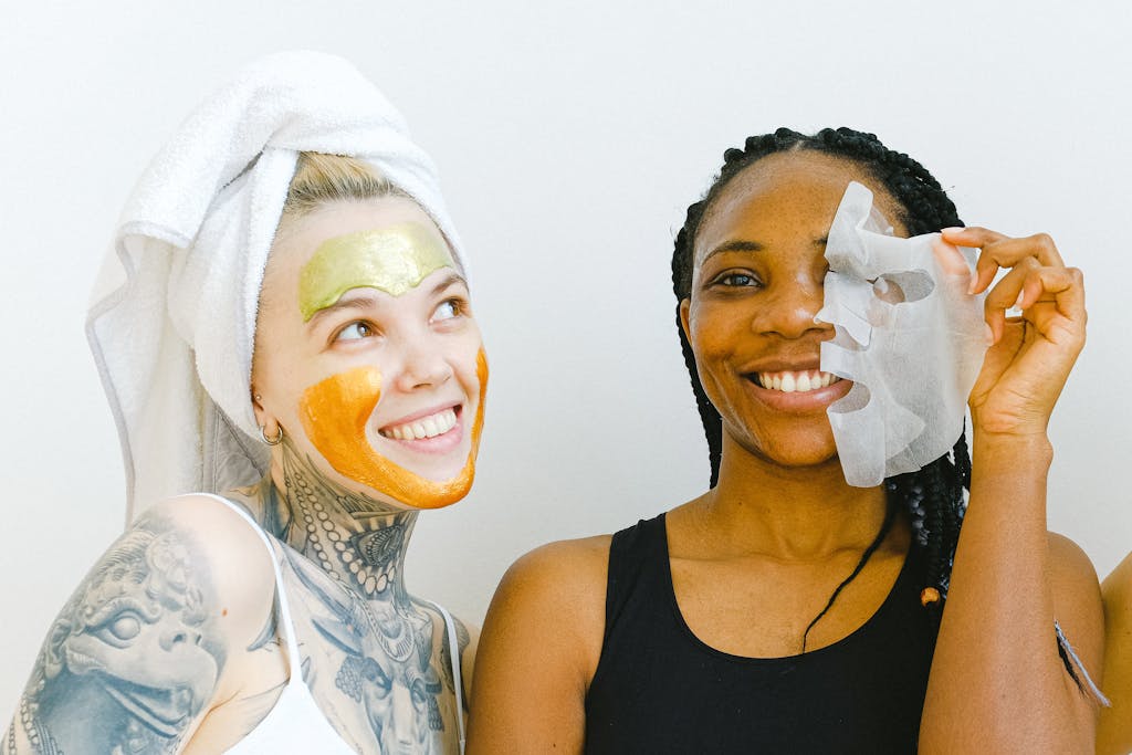 Two women sharing a joyful moment during their skincare ritual with facial masks.